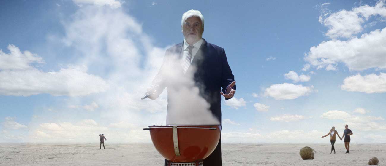 Lambassador Sam Kekovich appears in a cloud of smoke, alongside a sizzling BBQ and perfectly searing lamb.